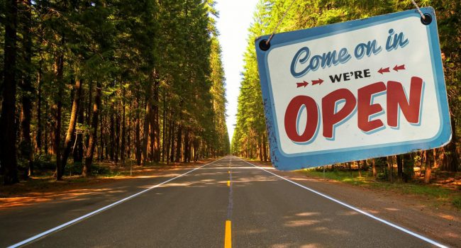 "Come on in we're open" sign over an open road